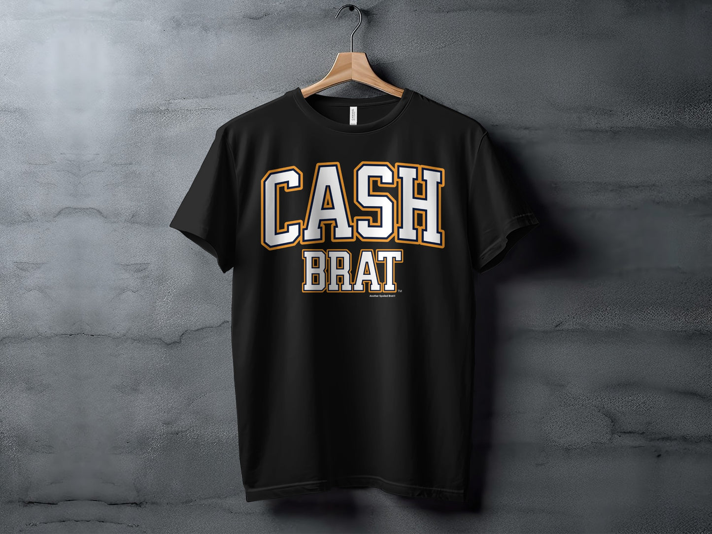 Black t-shirt with bold white and orange "CASH BRAT" lettering. TM symbol visible.