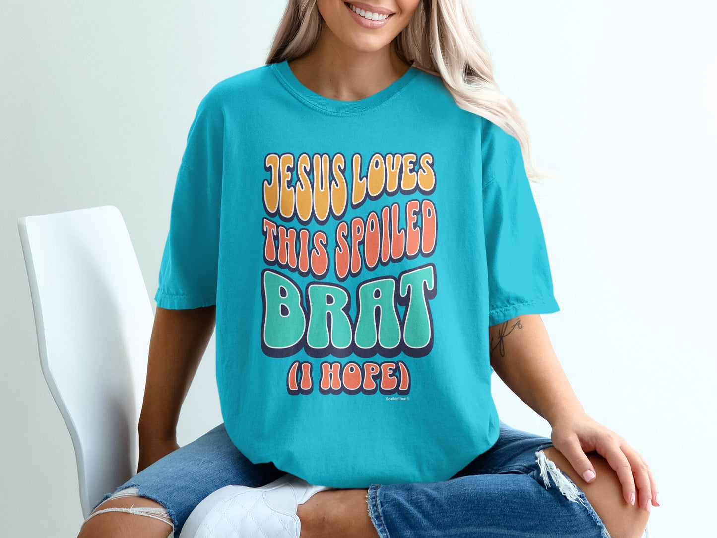 Teal t-shirt with "JESUS LOVES THIS SPOILED BRAT (I HOPE)" text.