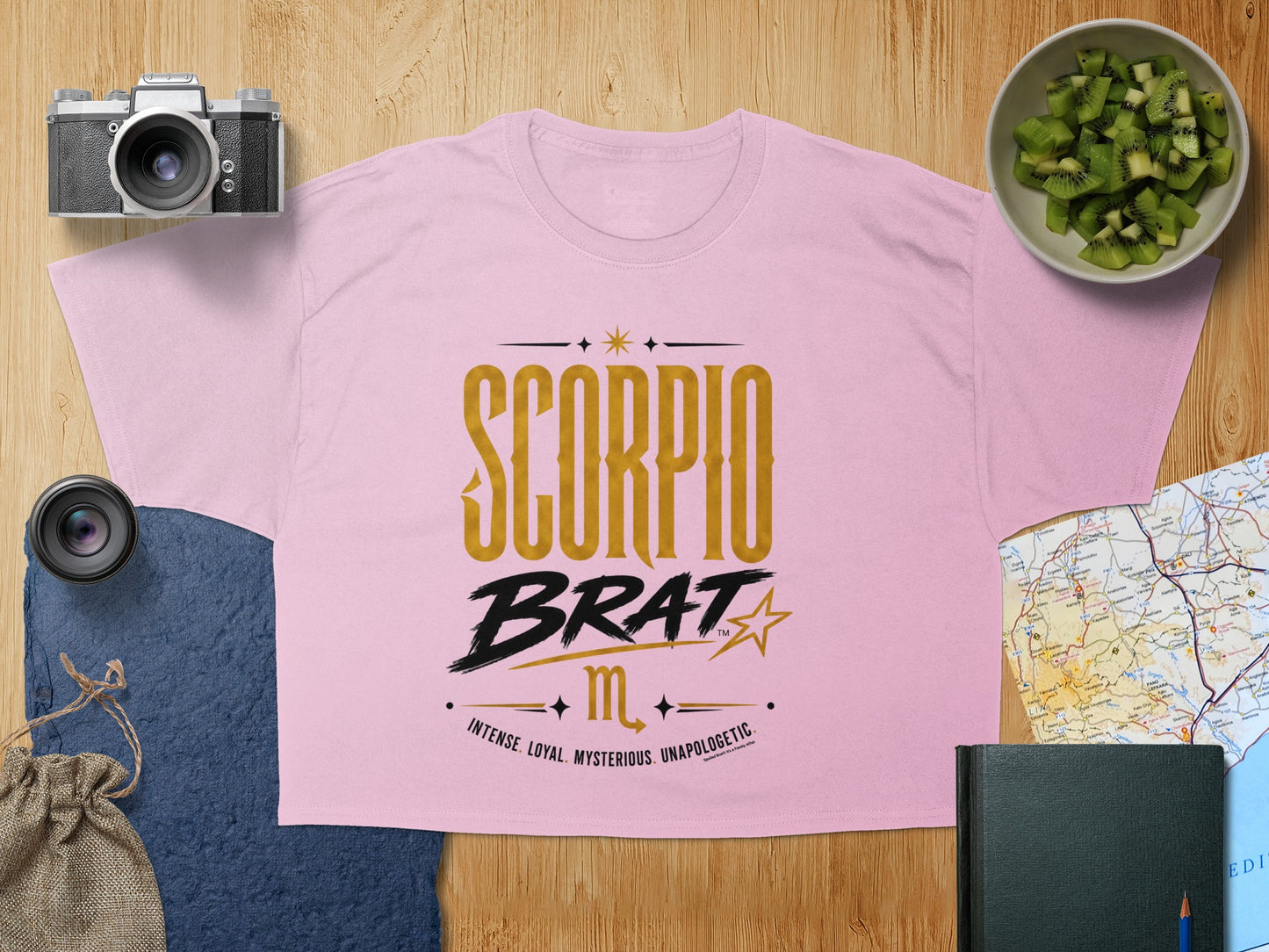Pink t-shirt with "Scorpio Brat" and astrological glyph printed in gold and black.
