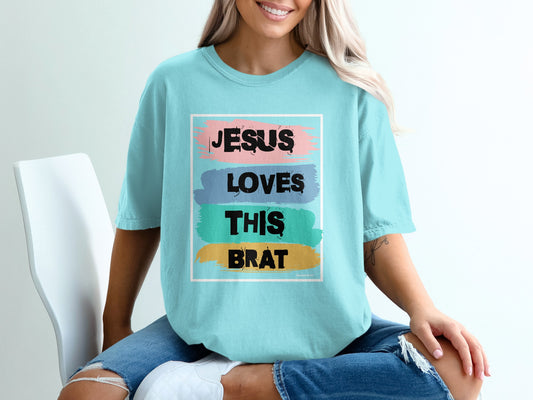 Teal t-shirt with "Jesus Loves This Brat" text in colorful block letters.