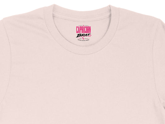 Capricorn Brat text and symbol centered on a light pink t-shirt collar.
