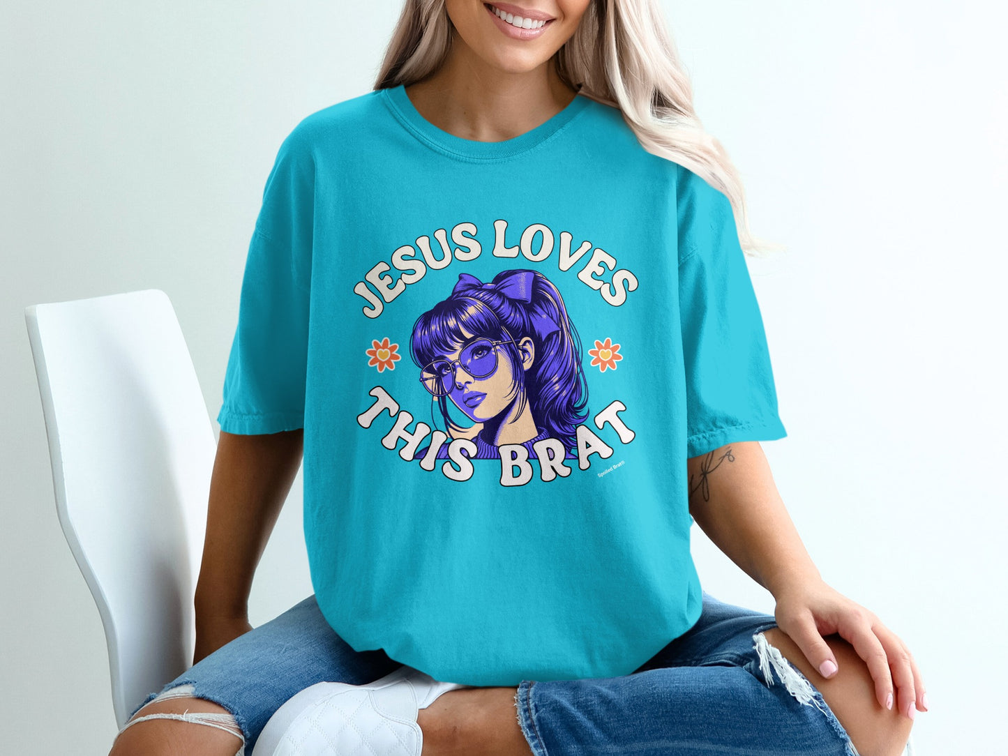Teal t-shirt with "Jesus Loves This Brat" text and cartoon girl graphic.