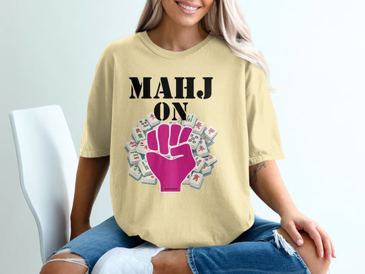 Mahjong tiles and fist graphic on yellow t-shirt worn by a woman.