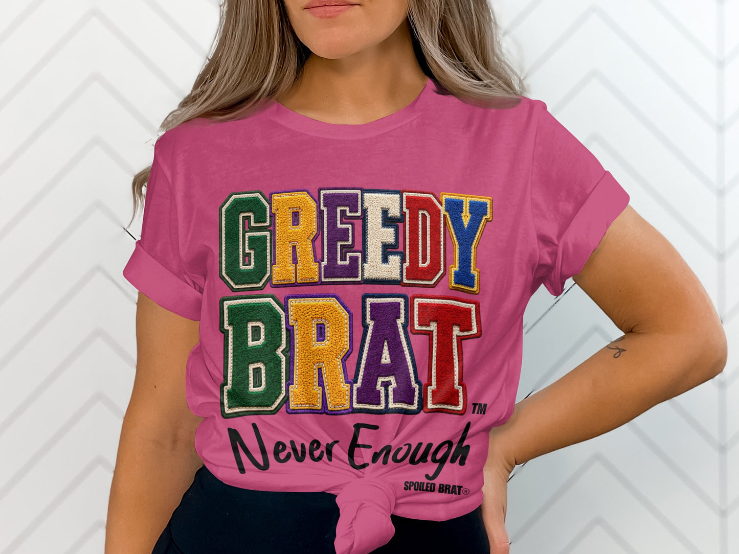 Pink t-shirt with "GREEDY BRAT" and "Never Enough" text.