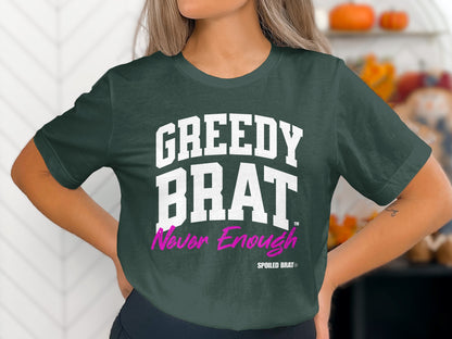 Dark green t-shirt with white "GREEDY BRAT" and pink "Never Enough" text.
