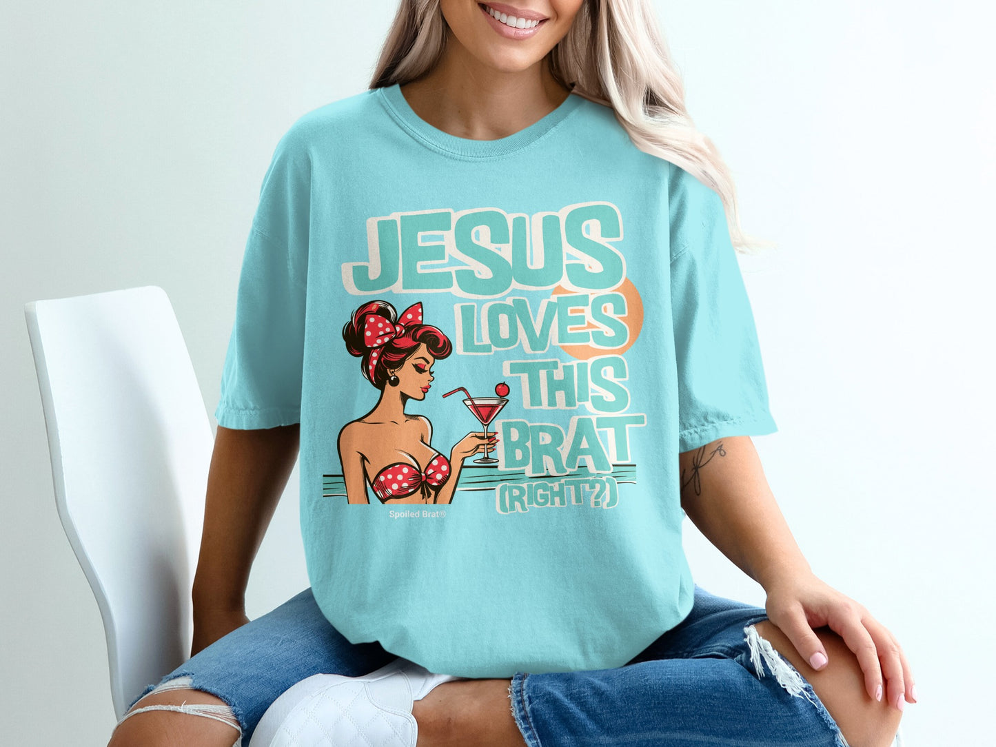 Teal t-shirt with graphic of a pin-up girl and text "JESUS LOVES THIS BRAT (RIGHT?)".