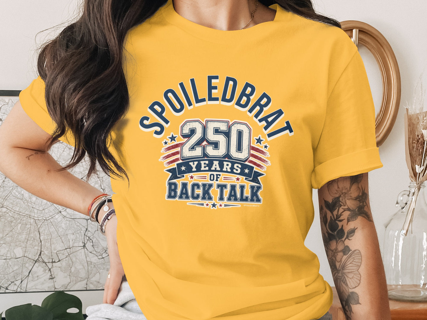 Yellow t-shirt with "Spoiledbrat 250 years of back talk" graphic.