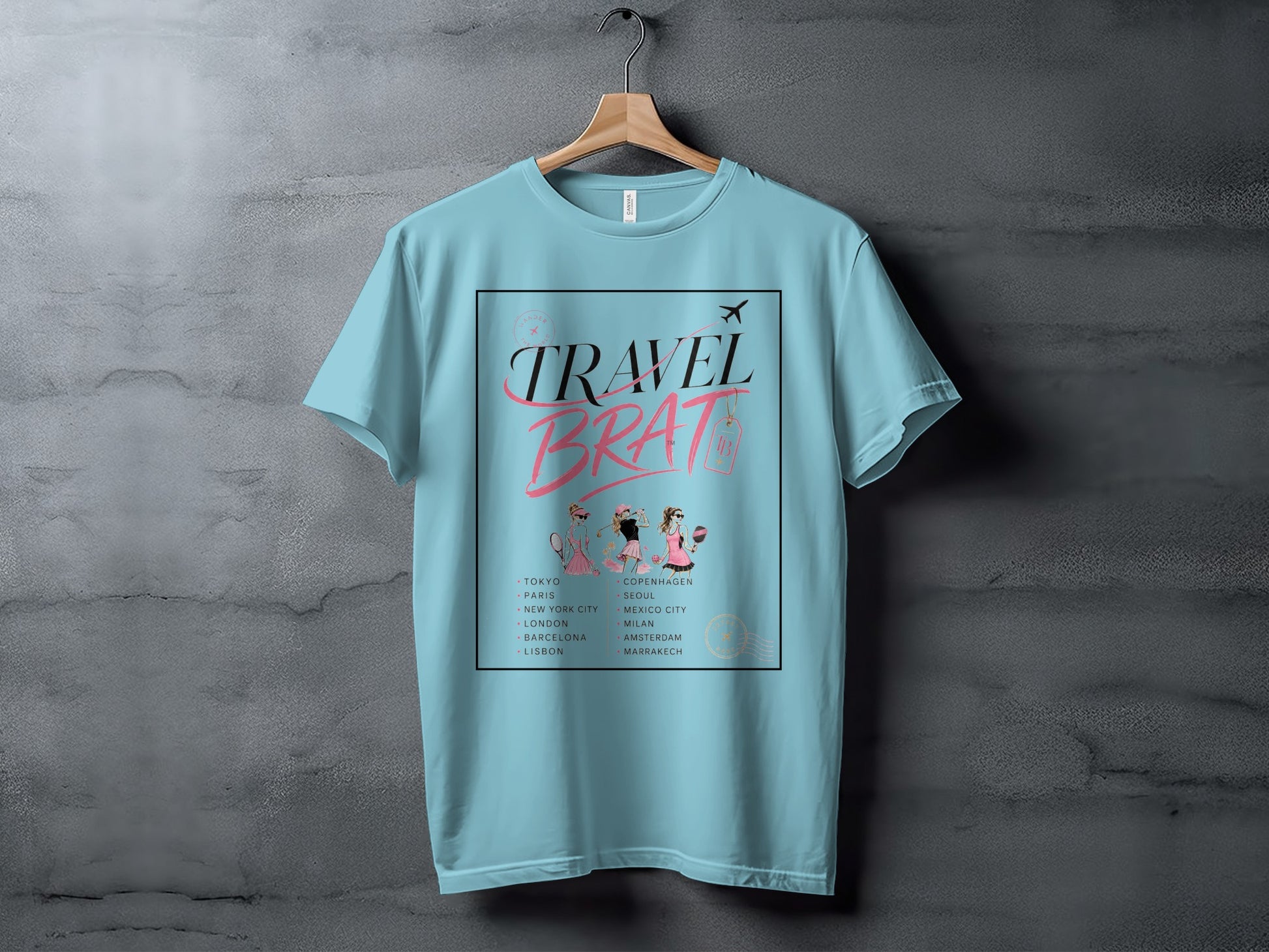 Light blue t-shirt with "TRAVEL BRAT" text and list of cities.