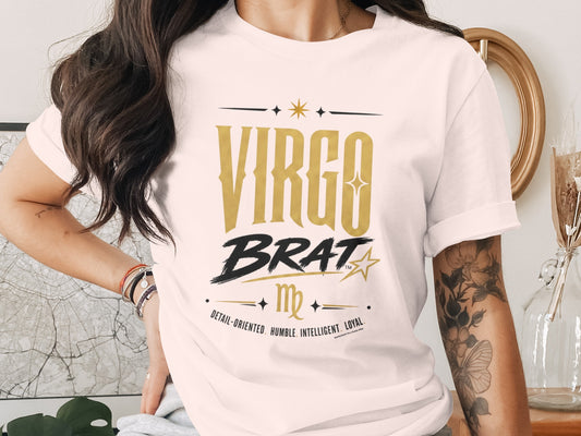 White t-shirt with "Virgo Brat" in gold, black, and text describing Virgo traits.