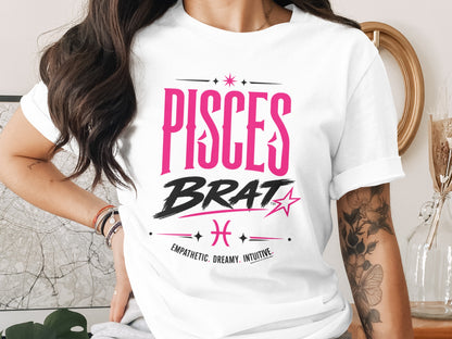 White t-shirt with "PISCES BRAT" text in pink and black, and "EMPATHETIC. DREAMY. INTUITIVE."