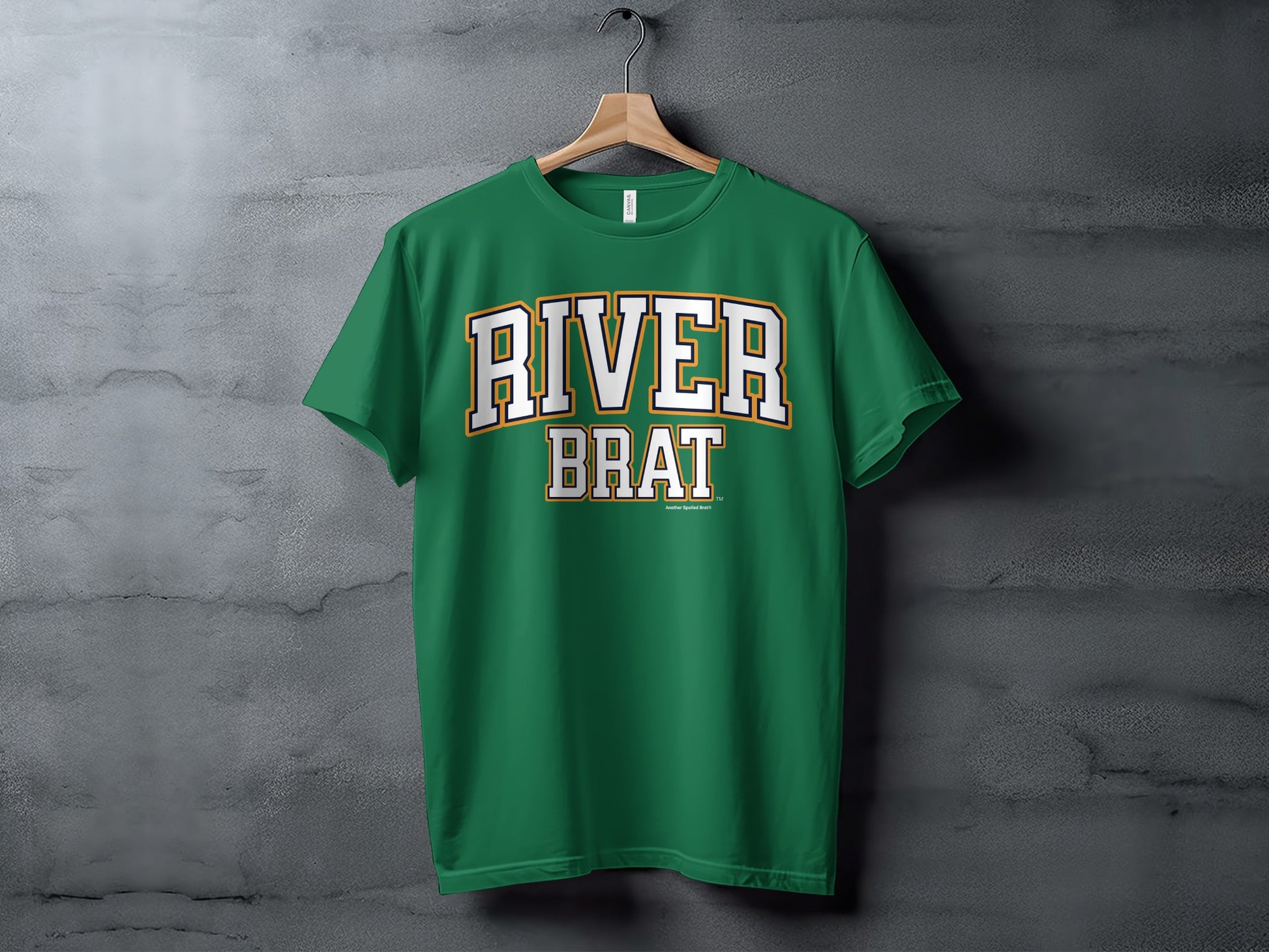 Green t-shirt with white and yellow "RIVER BRAT" text, hanging on a hanger.