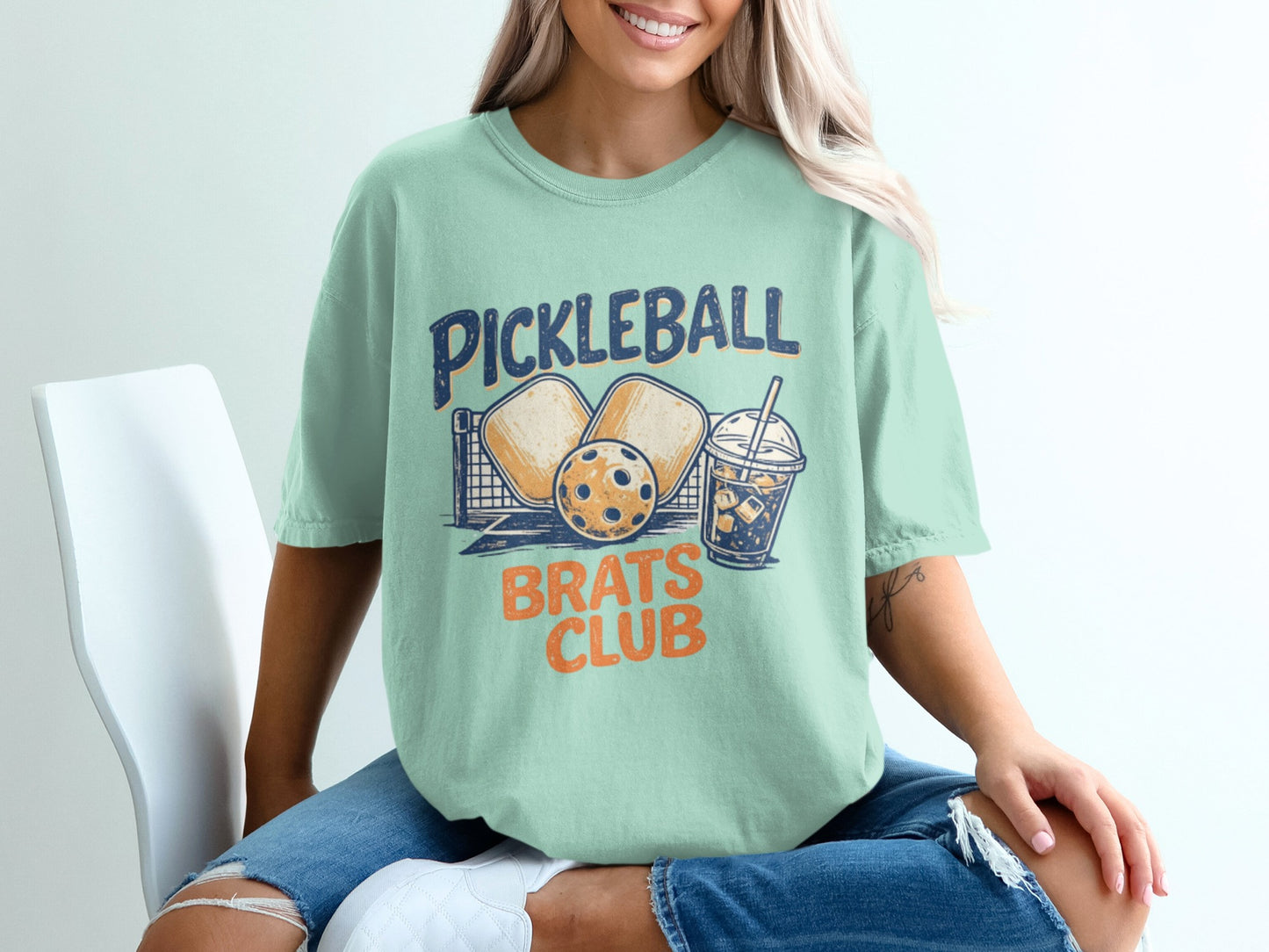 Pickleball Brats Club graphic on a mint green t-shirt with pickleball equipment.
