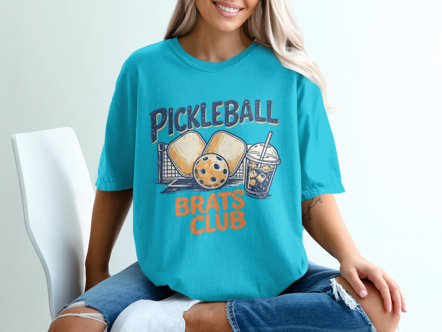 Turquoise t-shirt with "Pickleball Brats Club" text and graphics.