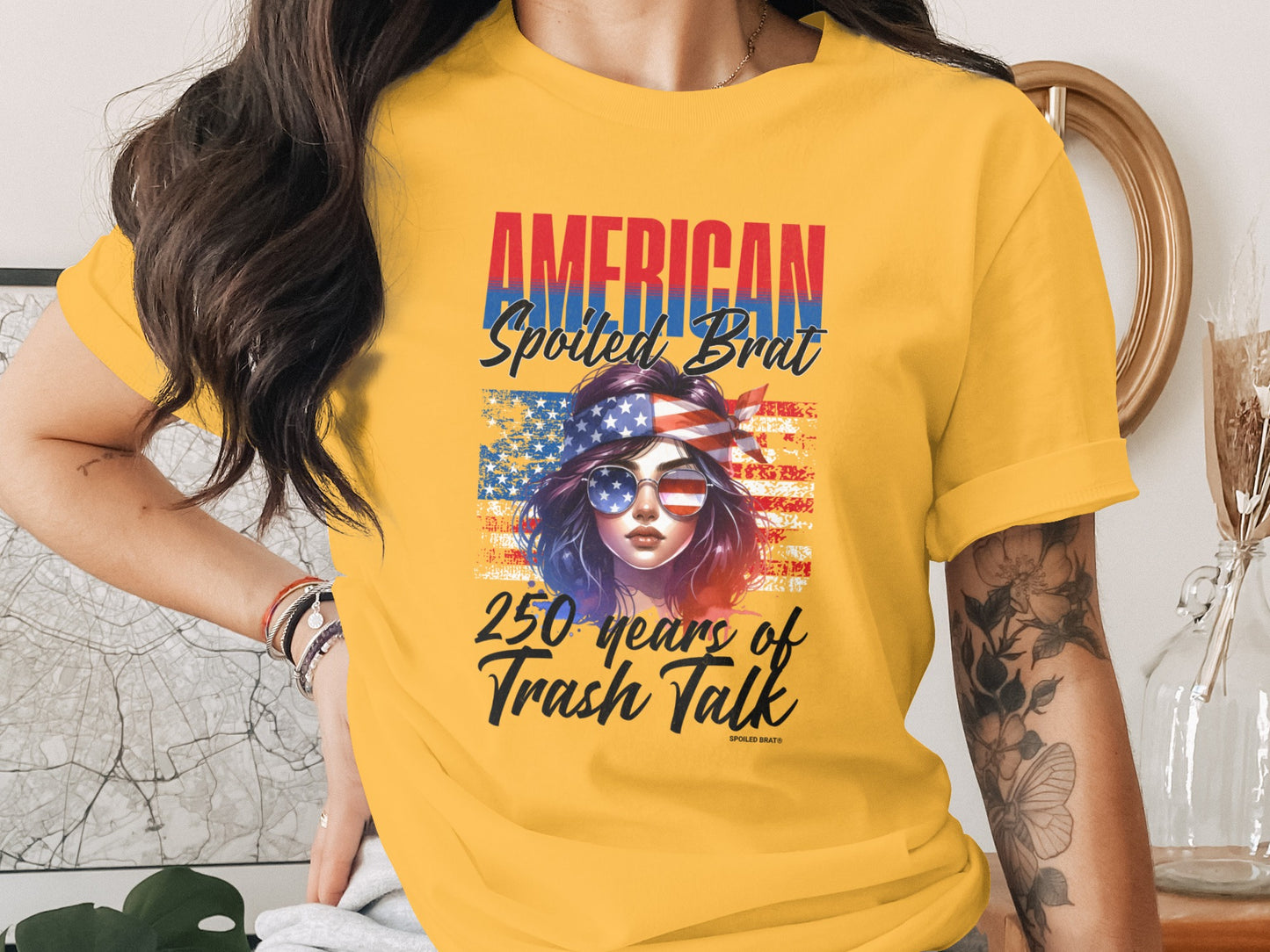 Yellow t-shirt with "AMERICAN Spoiled BRAT 250 Years of trash talk" graphic.