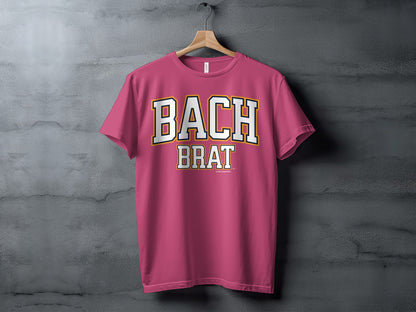 Pink t-shirt with "BACH BRAT" in white and gold block letters.