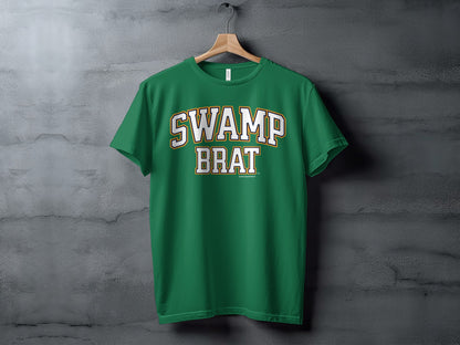 Green t-shirt with white and gold "SWAMP BRAT" text on chest.