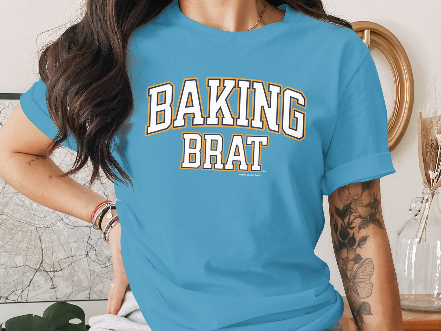 Blue t-shirt with white text "BAKING BRAT" in collegiate style font.