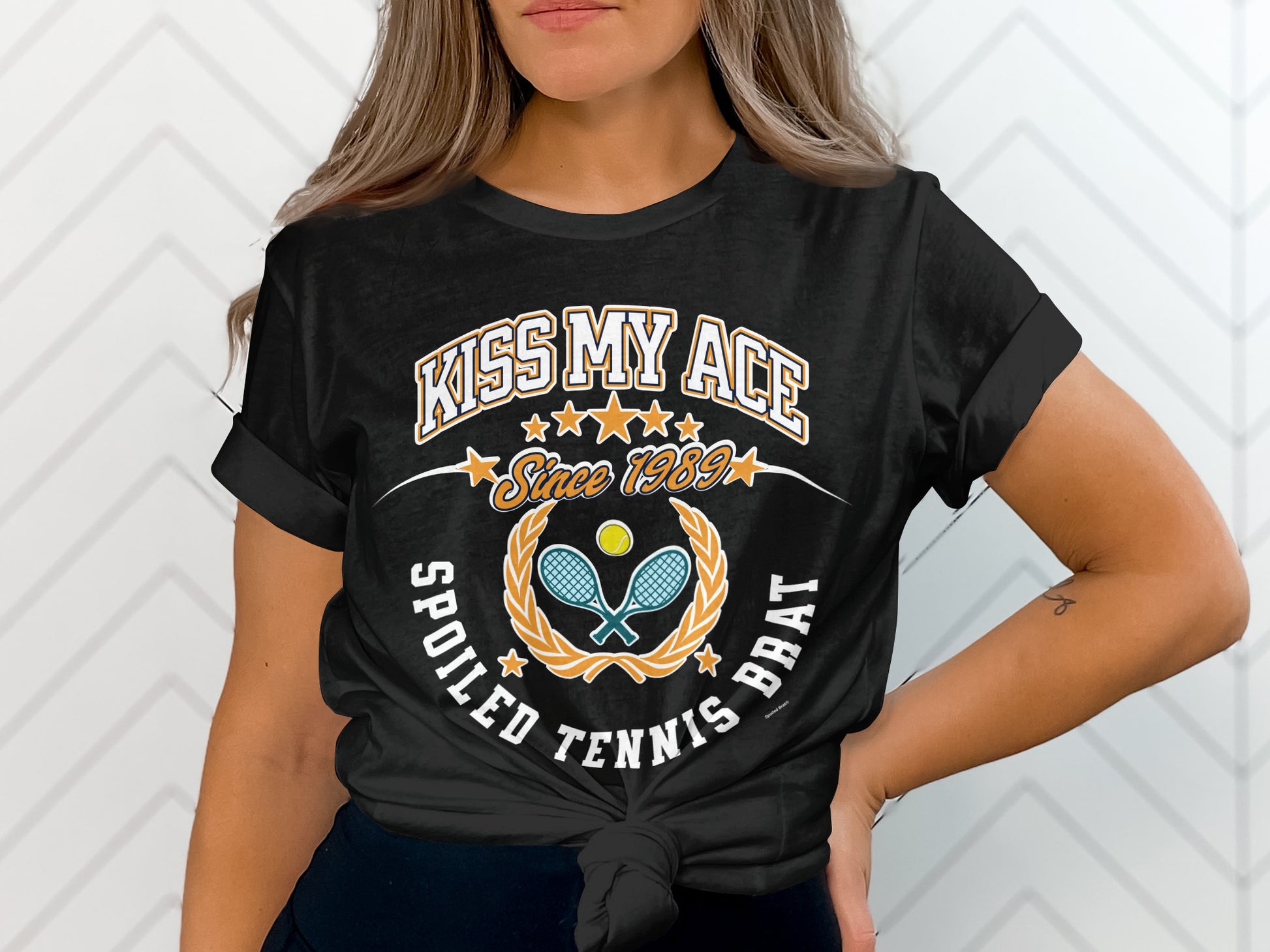 Black t-shirt with "Kiss My Ace Since 1989 Spoiled Tennis Brat" and tennis graphics.