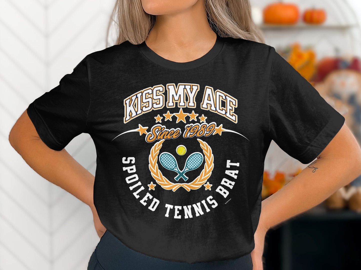 Black t-shirt with "Kiss My Ace Since 1989 Spoiled Tennis Brat" text and tennis graphic.