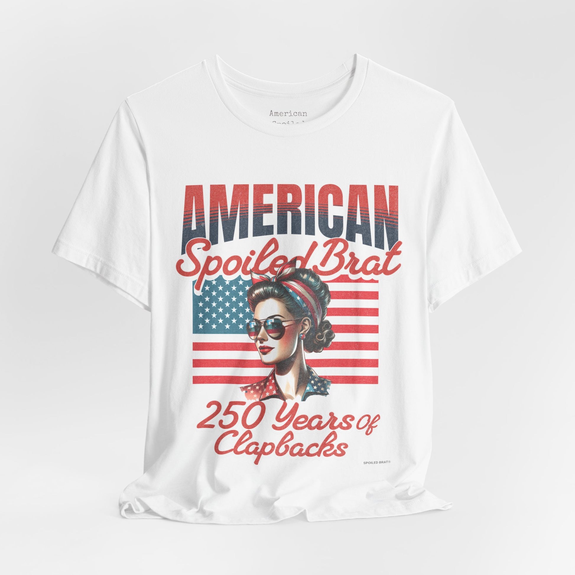 White t-shirt with "American Spoiled Brat 250 Years of Clapbacks" and patriotic woman.
