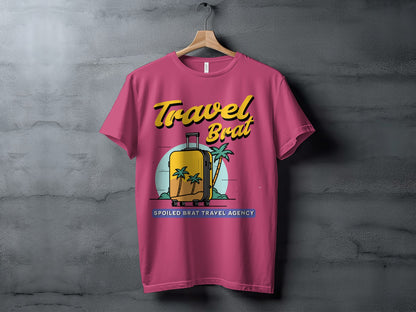 Pink t-shirt with "Travel Brat Spoiled Brat Travel Agency" text and suitcase graphic.