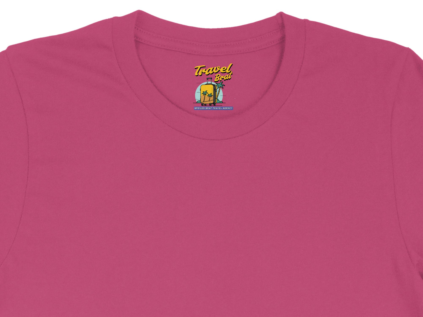 Pink t-shirt with "Travel Brat" logo featuring a suitcase, palm trees, and "Spoiled Brat Travel Agency".