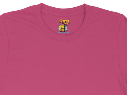 Pink t-shirt with "Travel Brat" logo featuring a suitcase, palm trees, and "Spoiled Brat Travel Agency".