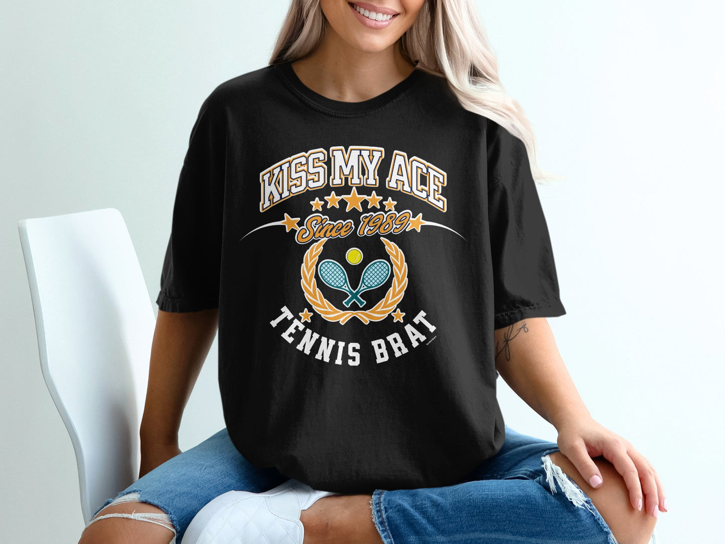 Black t-shirt with "Kiss My Ace Since 1959 Tennis Brat" text and crossed tennis rackets.
