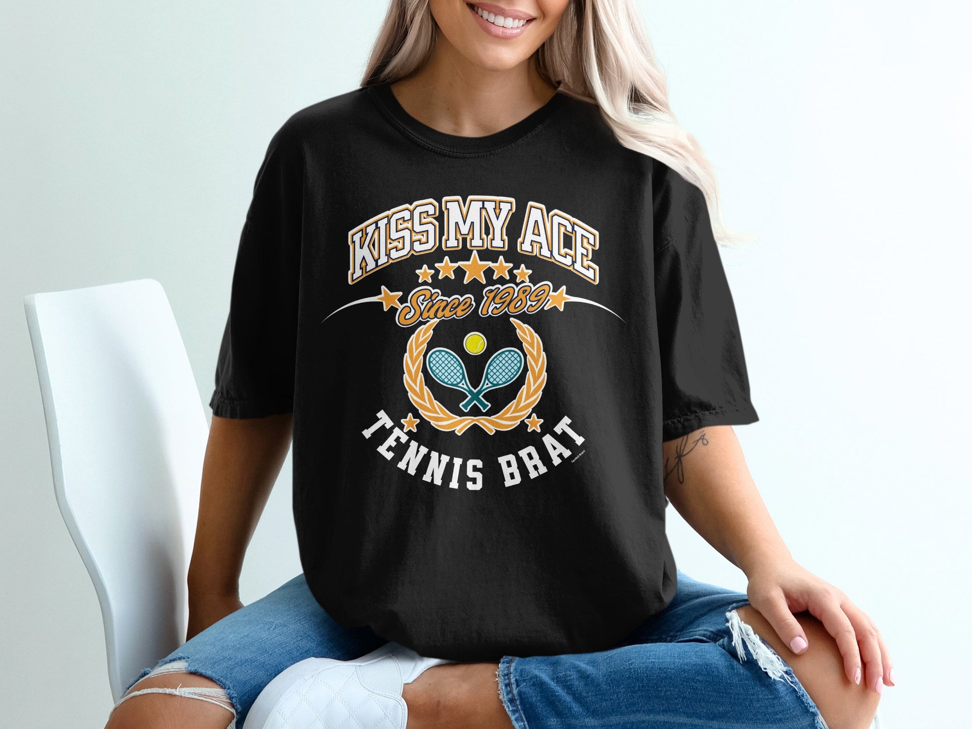 Black t-shirt with "Kiss My Ace Since 1959 Tennis Brat" text and crossed tennis rackets.
