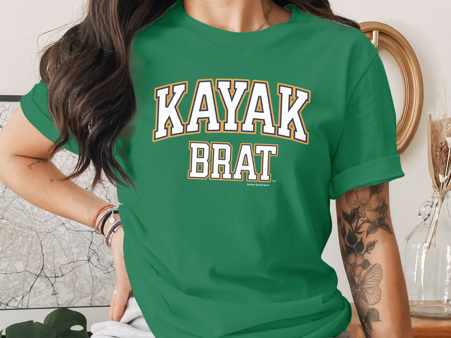 Green t-shirt with "KAYAK BRAT" text and "Another Spoiled Brat" logo.