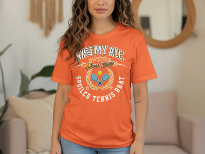 Orange t-shirt with "KISS MY ACE SINCE 1989 SPOILED TENNIS BRAT" text and tennis graphics.