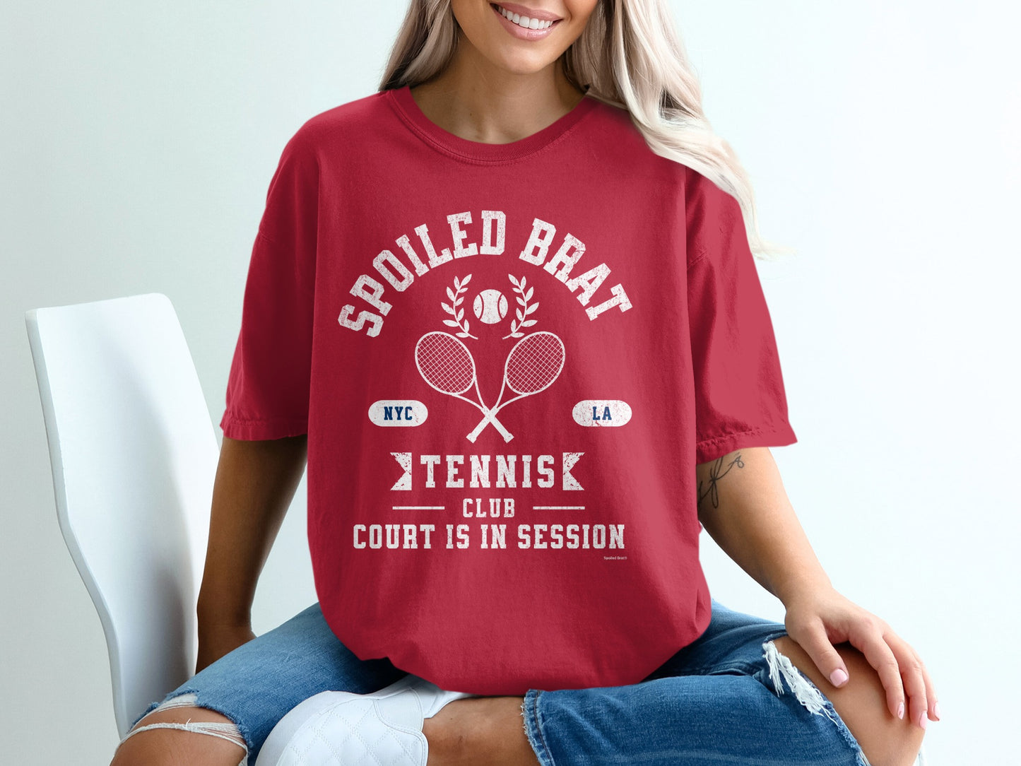 Red t-shirt with "Spoiled Brat Tennis Club" graphic.