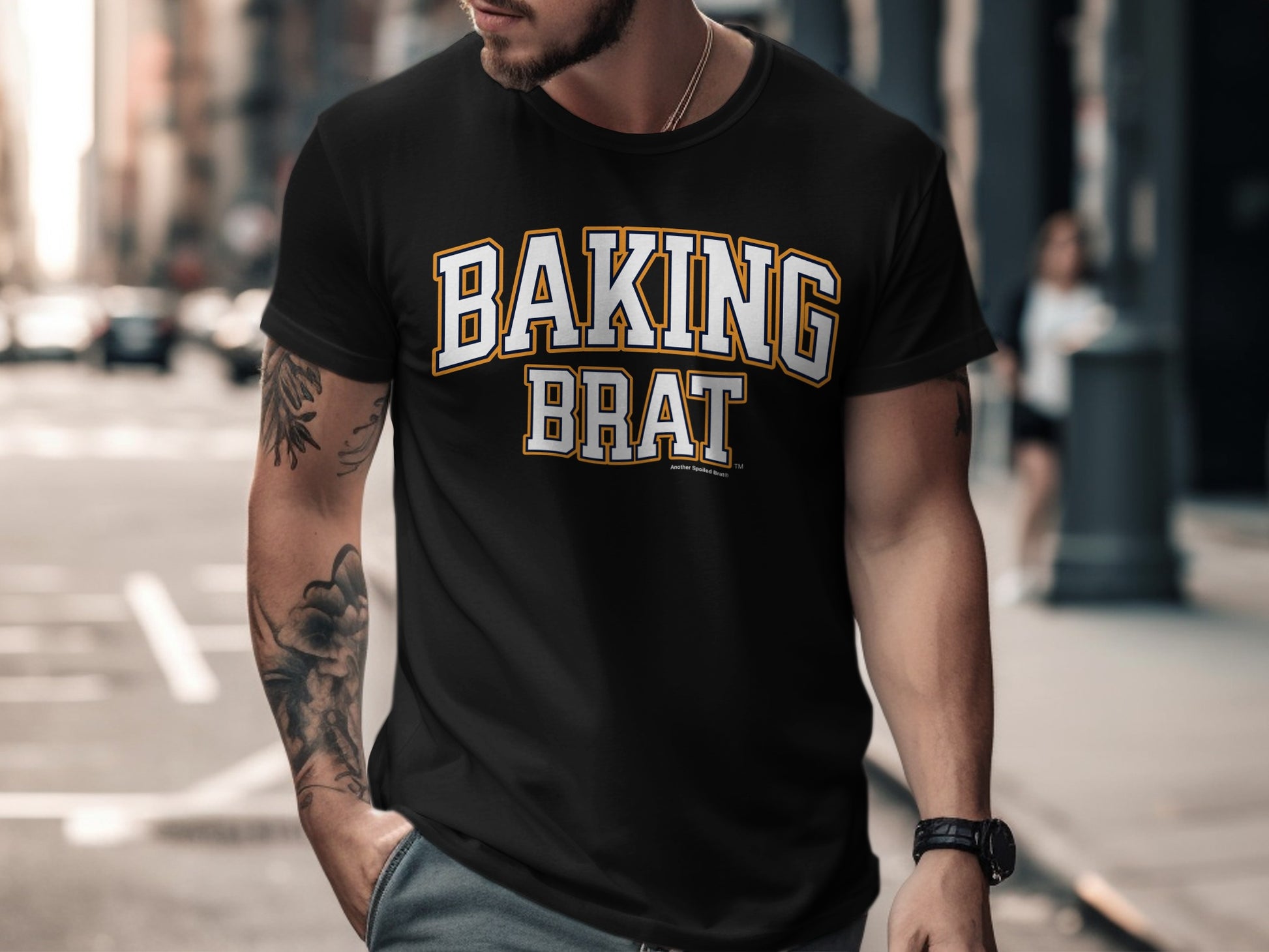 Black t-shirt with "BAKING BRAT" in white, yellow, and navy lettering.