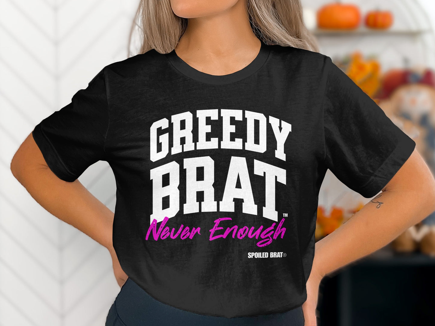 Black t-shirt with white "GREEDY BRAT" text and pink "Never Enough" text.