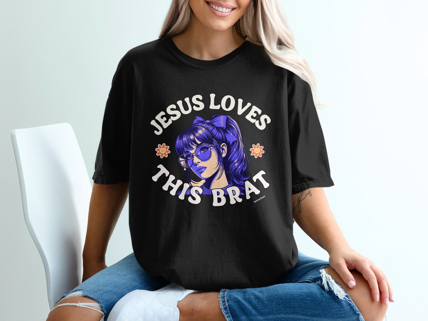 Black t-shirt with "Jesus Loves This Brat" text and cartoon girl graphic.