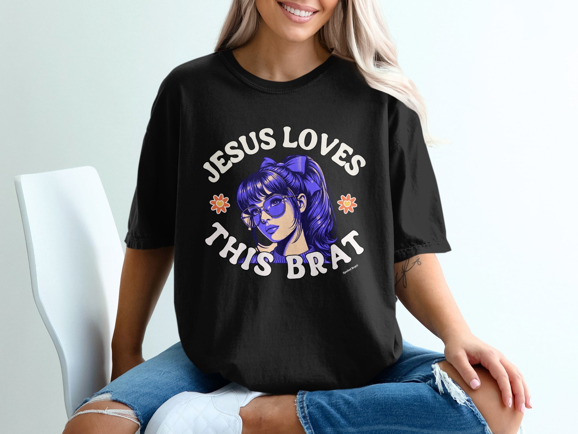 Black t-shirt with "Jesus Loves This Brat" text and cartoon girl graphic.