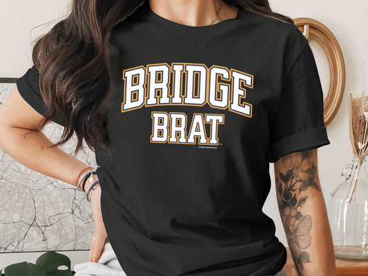 Black t-shirt with "BRIDGE BRAT" text in white and yellow collegiate lettering.