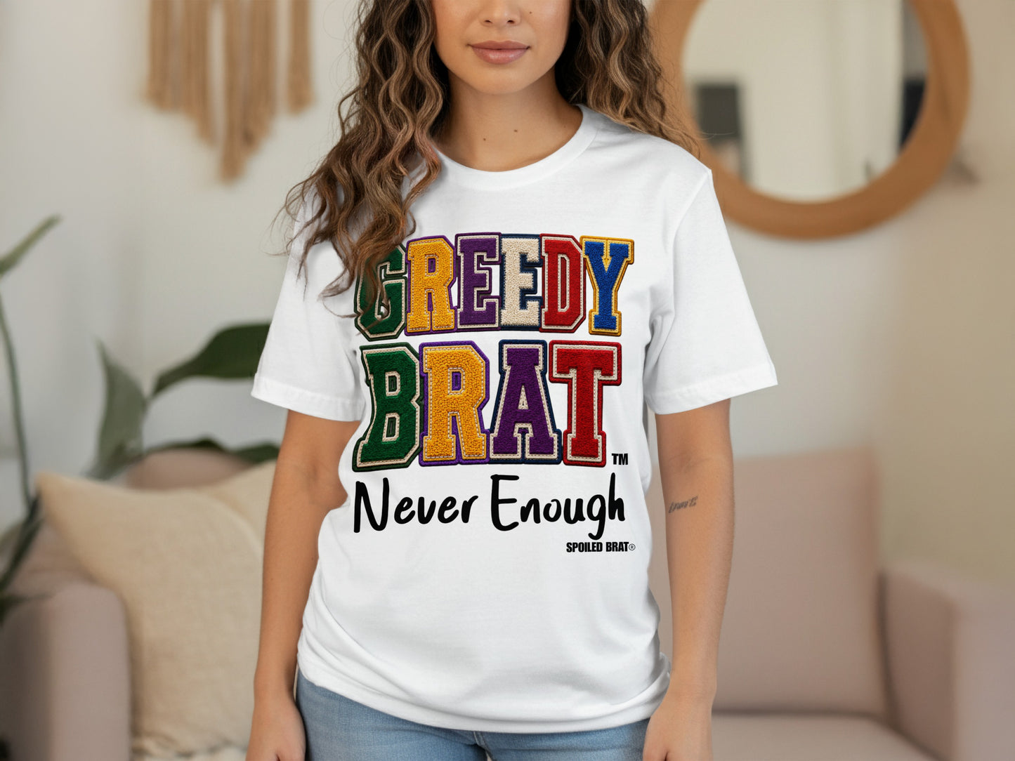 White t-shirt with colorful "GREEDY BRAT" text and "Never Enough" below.