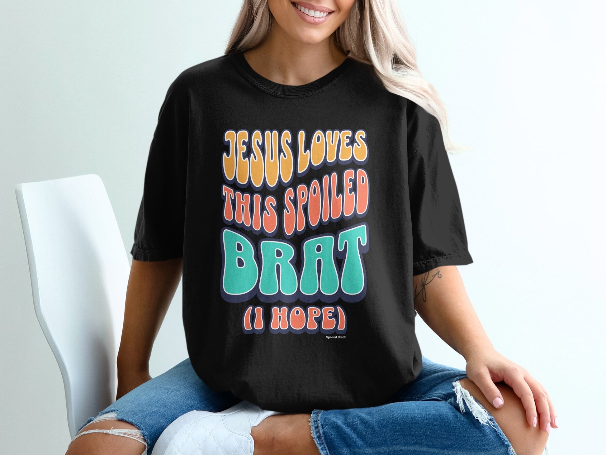 Black t-shirt with "JESUS LOVES THIS SPOILED BRAT (I HOPE)" text.