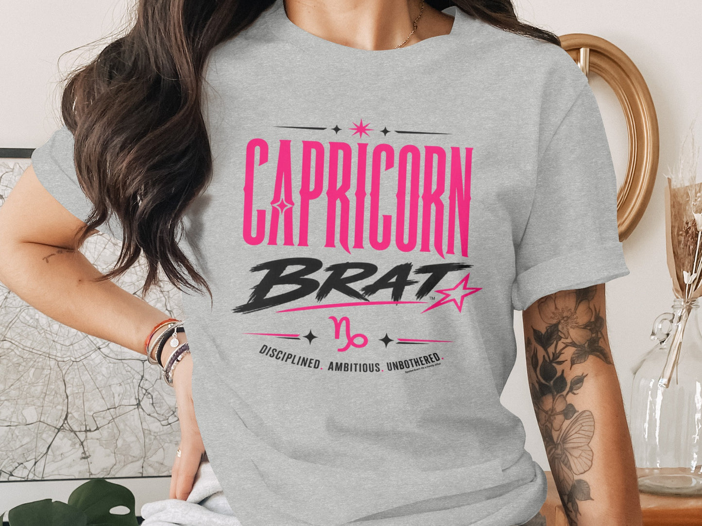 Grey t-shirt with pink text "CAPRICORN BRAT" and Capricorn symbol.