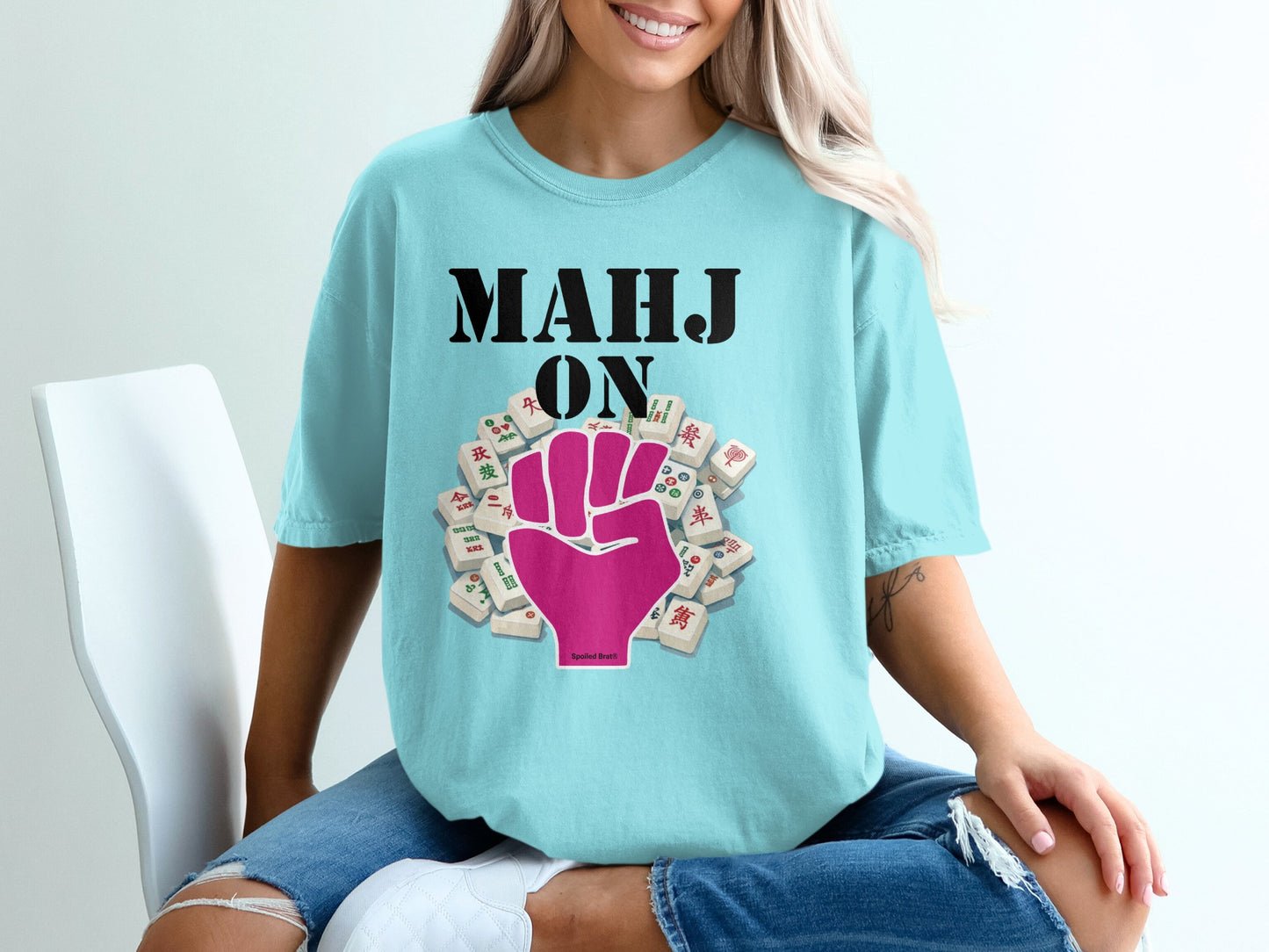 Light blue t-shirt with "MAHJ ON" and pink fist with mahjong tiles.