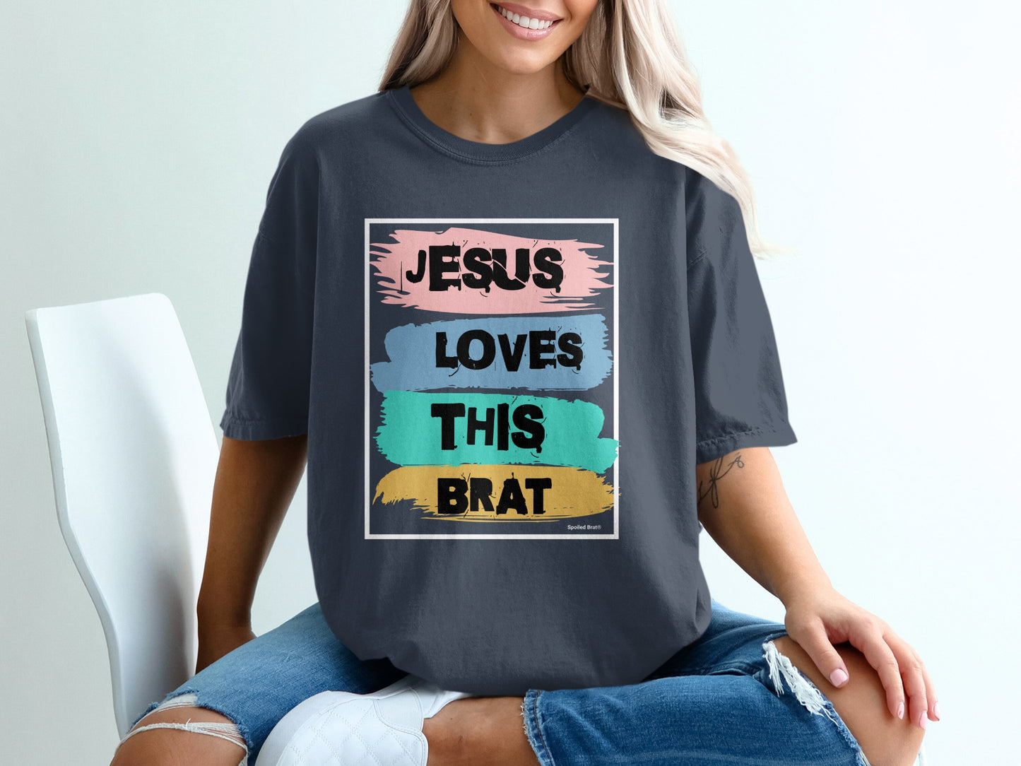 Dark t-shirt with "Jesus Loves This Brat" text in colorful painted strokes.