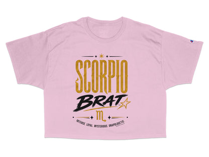 Pink Champion crop top with gold "SCORPIO BRAT" graphic and zodiac symbol.