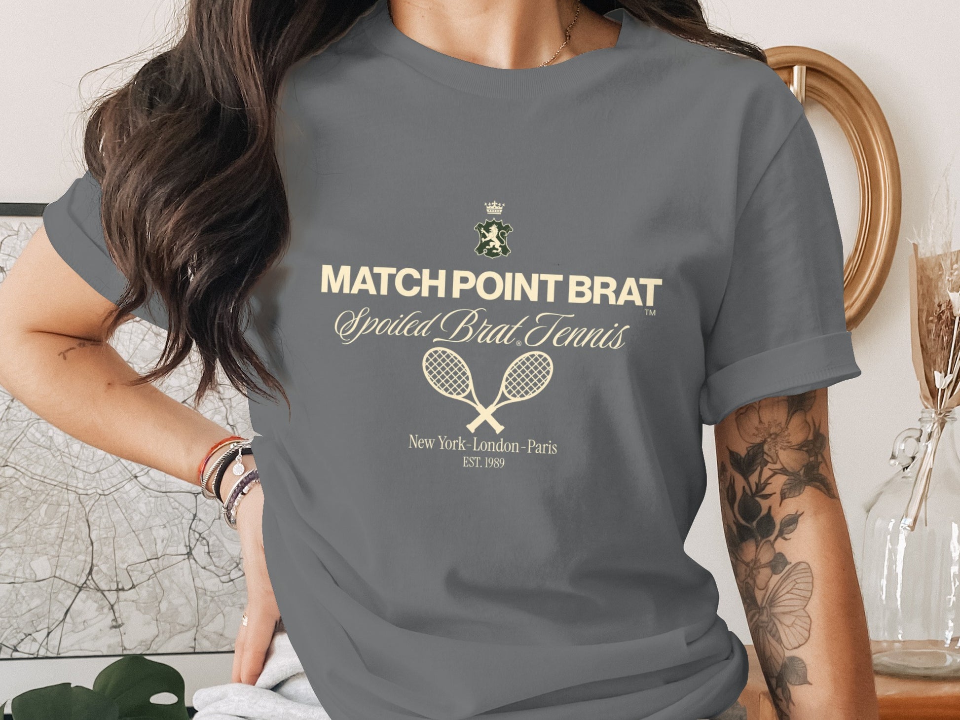 Grey t-shirt with "Match Point Brat" text, tennis rackets, and "Est. 1989" in beige.