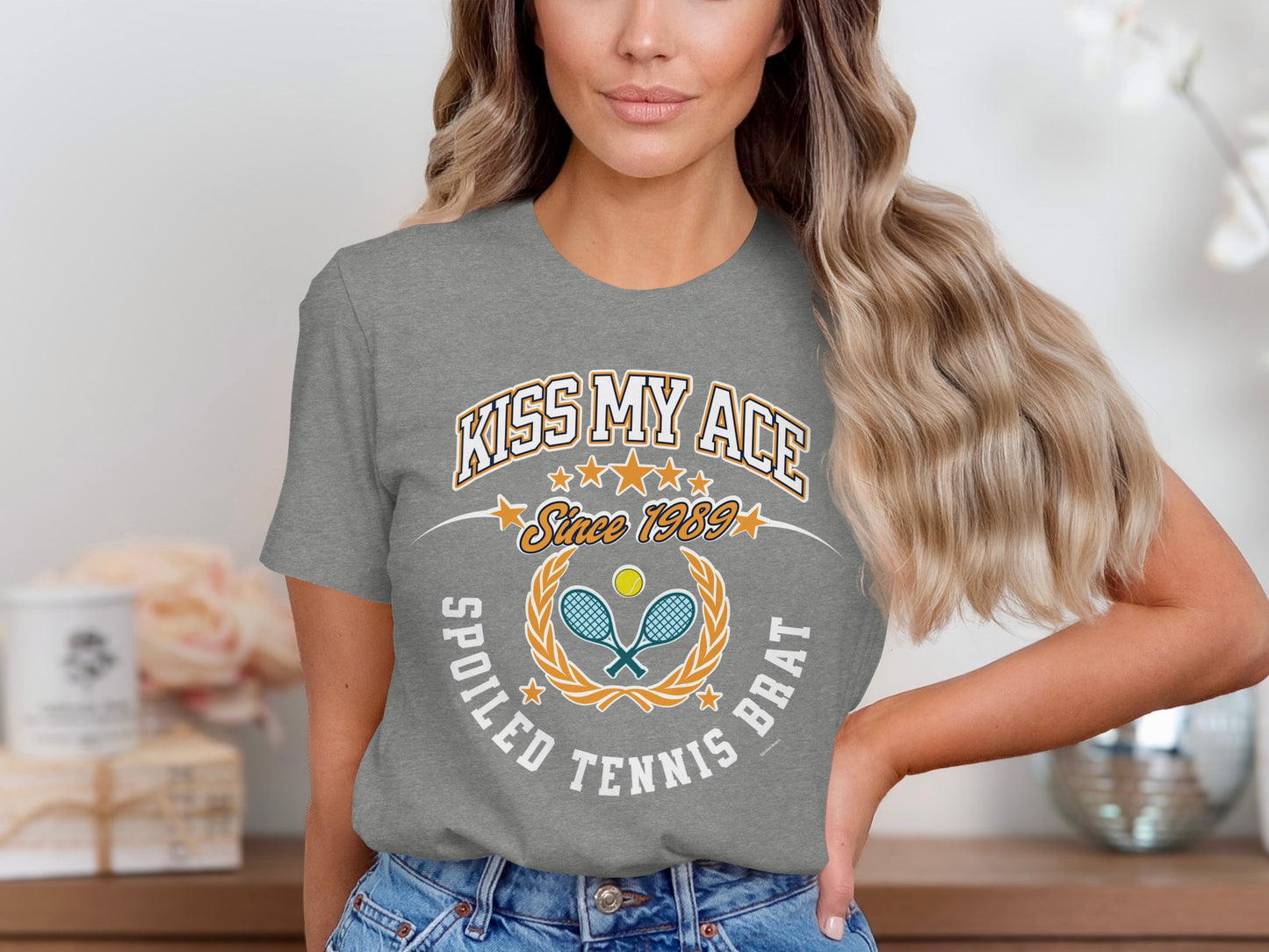 Grey t-shirt with "Kiss My Ace Since 1989 Spoiled Tennis Brat" graphic.