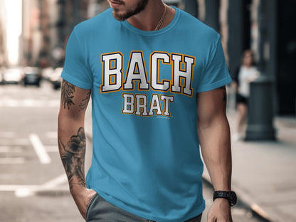 Blue t-shirt with "BACH BRAT" text in white, orange, and black collegiate style font.