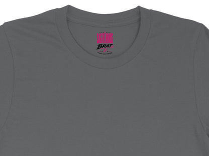 Dark grey t-shirt neck label with pink "BRAT" text and "Adventurous Honest Freedom-Loving".