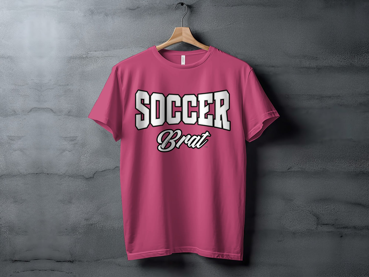 Pink t-shirt with white "SOCCER" and "Brat" text on a hanger.