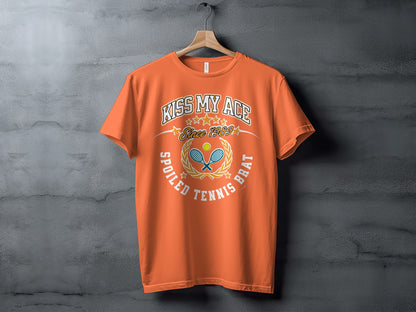 Orange t-shirt with "Kiss My Ace Since 1989 Spoiled Tennis Brat" text and graphics.