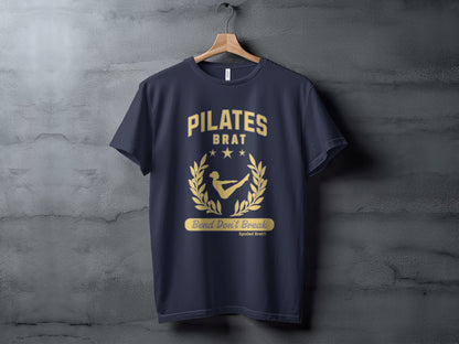 Dark navy t-shirt with gold "PILATES BRAT Bend Don't Break" graphic.